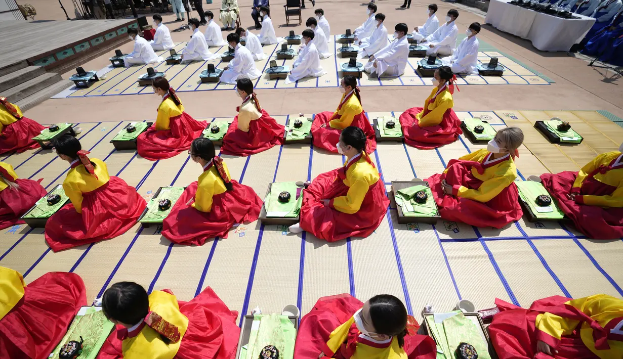 Wanita dan pria mengenakan gaun tradisional Korea Selatan membungkuk selama upacara untuk menghidupkan kembali Hari Kedewasaan ke-50 di Desa Hanok Namsangol di Seoul, Korea Selatan (16/5/2022). Upacara diadakan untuk pria dan wanita muda yang akan berusia 20 tahun. (AP Photo/Lee Jin-man)
