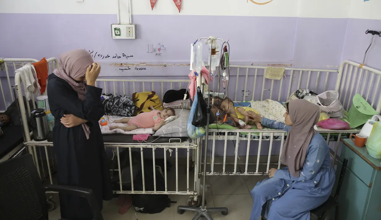 Amira Al-Jojo (kiri) berdiri di samping putranya yang berusia 10 bulan, Yousef Al-Jojo, yang menderita kekurangan gizi di Rumah Sakit Martir Al-Aqsa, tempat ia menjalani perawatan, di Deir al-Balah di Jalur Gaza tengah pada Sabtu, 1 Juni 2024. (AP Photo/ Jehad Alshrafi)