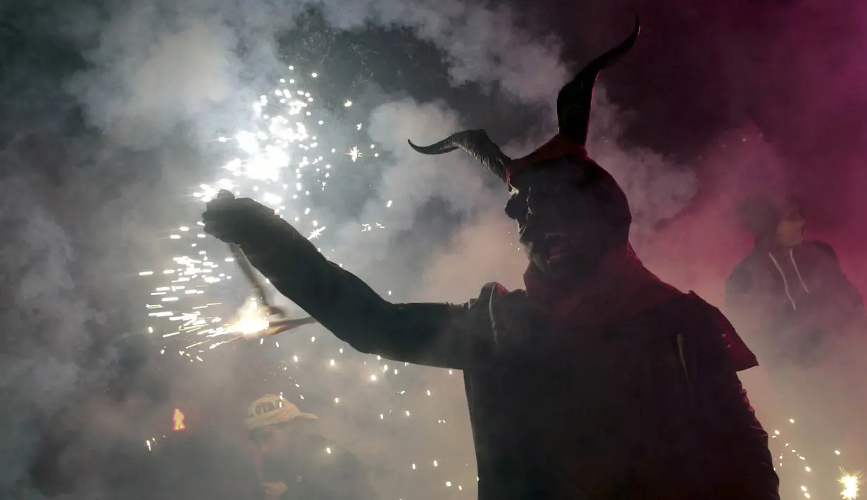 Seorang warga berpakaian seperti hantu dengan memegang tongkat kembang api selama perayaan " Correfocs ", Mallorca, Spanyol, (24/1). Ini merupakan perayaan tradisional yang menandai menandai akhir dari perayaan lokal di Palma. (REUTERS / Enrique Calvo)