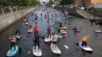 Sejumlah peserta mengenakan kostum mendayung papan Stand Up Paddle (SUP) di kanal Kryukov saat Surfing festival di St.Petersburg, Rusia (8/7). Dalam acara ini mereka mengenalkan olahraga air baru yang mirip Surfing. (AP Photo / Dmitri Lovetsky)