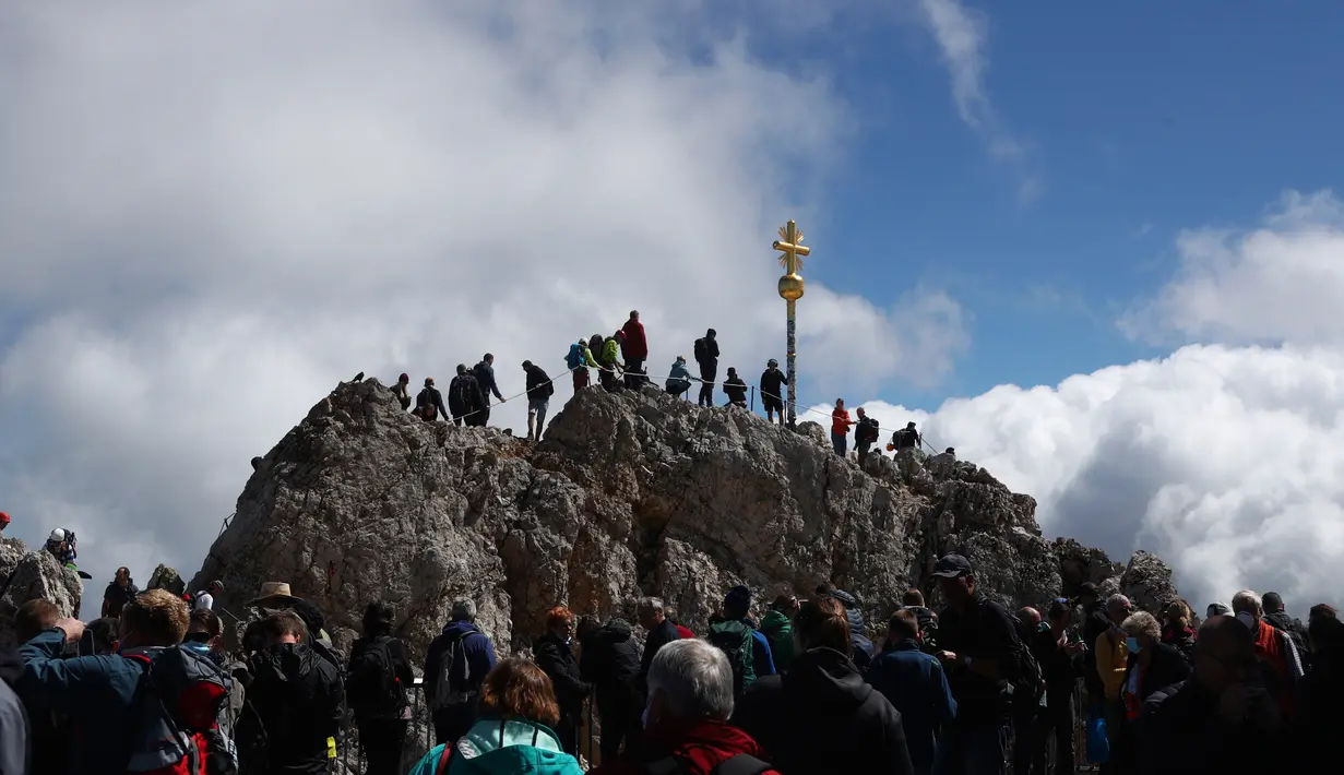 Orang-orang mengantre untuk mencapai puncak salib di puncak gunung tertinggi Jerman, Zugspitze, dekat Garmisch-Partenkirchen, Jerman pada 19 Agustus 2020. Setiap tahunnya gunung dengan ketinggian 2.962 meter tersebut membuat sekitar setengah juta pengunjung terpesona. (AP Photo/Matthias Schrader)