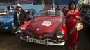 Dua wanita berpose disamping sebuah mobil antik selama acara Reli Mobil Antik Statesman (Statesman Vintage Car Rally) di Kolkata, India (19/1/2020). Lebih dari 180 mobil dan kendaraan roda dua antik ambil bagian dalam reli mobil klasik dan antik pada acara tersebut. (Xinhua/Tumpa Mondal)