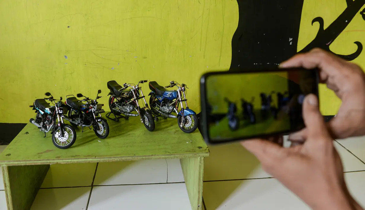 Seorang pekerja memotret miniatur sepeda motor di bengkel kerjanya di Kelurahan Serua, Tangerang Selatan, Banten (10/10/2020). Di sana, miniatur sepeda motor yang terbuat dari bahan-bahan daur ulang dijual kepada pelanggan sebagai hadiah atau hiasan. (Xinhua/Agung Kuncahya B.)