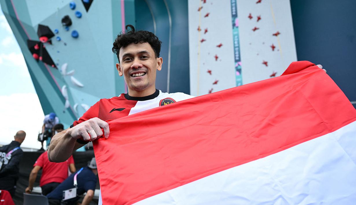 Atlet panjat tebing Indonesia, Veddriq Leonardo membentangkan bendera Merah Putih saat merayakan kemenangan pada babak final cabang olahraga pajat tebing nomor speed Olimpiade Paris 2024 di Le Bourget Sport Climbing Venue, Paris, Prancis, Kamis (08/08/2024). (AFP/Jonathan Nackstrand)