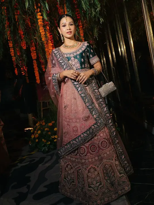 Andien mengenakan lehenga berwarna-warni dengan kombinasi hijau tua, pink, dan nuansa emas yang elegan, menampilkan desain yang begitu artistik dan megah. [@andienaisyah].