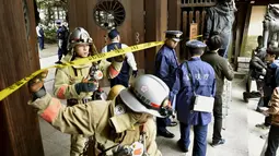 Petugas Polisi dan pemadam kebakaran saat melakukan investigasi di gerbang selatan Yasukuni Shrine dimana ledakan terjadi, Tokyo, Jepang, (23/11). Kuil ini merupakan simbol militerisme Jepang di masa lalu (REUTERS/Kyodo)