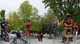 Warga berjalan melihat sejumlah robot mirip karakter film Transformers yang dipamerkan di pusat kota Zagreb, Kroasia (18/4). Robot ini dibuat dengan memanfaatkan bangkai mobil rusak akibat kecelakaan. (REUTERS/Antonio Bronic)