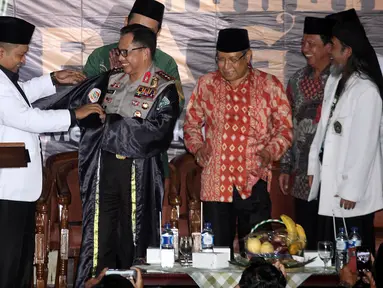 Sekjen Pagar Nusa M Nabil Haroen memberikan jubah kehormatan pencak silat Nahdlatul Ulama (PSNU) Pagar Nusa kepada Kapolri Jendral Tito Karnavian pada acara pembukaan Kongres III PSNU di TMII, Jakarta, Rabu (3/5). (Liputan6.com/Johan Tallo)