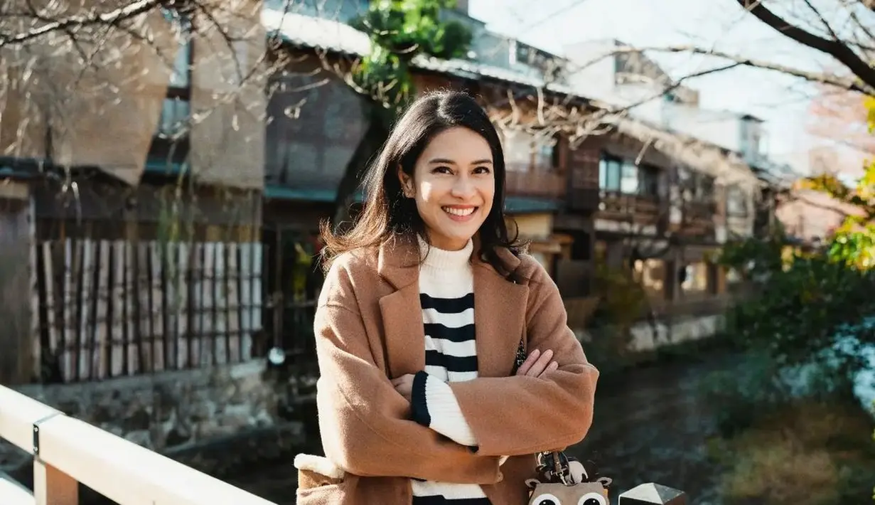 Dian Sastro menghabiskan momen liburan akhir tahunnya di Jepang. Terlihat ia mengenakan turtleneck sweater bermotif garis hitam-putih, ditumpuknya dengan long coat cokelat, dipadu dengan celana jeans, dan sneakers putih. Foto: Instagram.