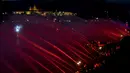 Petugas pemadam kebakaran menyemprotkan air ke Sungai Vltava berhias cahaya merah untuk menandai HUT ke-100 Ceko di Praha, Sabtu (2/6). (Michal Cizek/AFP)