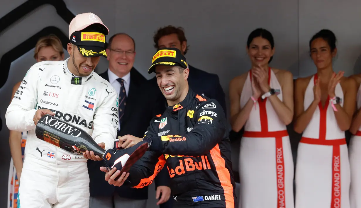 Pembalap Mercedes Lewis Hamilton menuangkan sampanye ke sepatu pembalap Red Bull Daniel Ricciardo usai balapan Grand Prix Monaco Formula 1, Monaco (27/5). Ricciardo saat ini menempati posisi kelima klasemen. (AP/Luca Bruno)