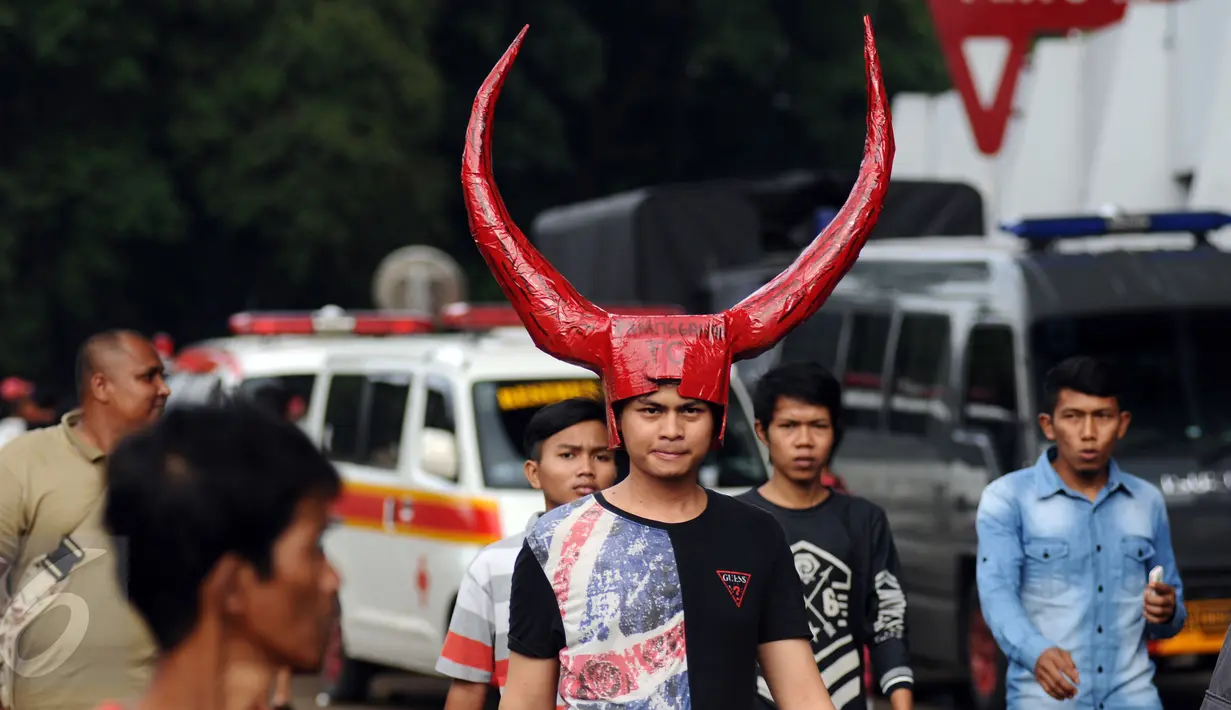 Seorang suporter Semen Padang memakai tanduk raksasa saat memasuki areal Stadion GBK Jakarta, Minggu (24/1/2016). Semen Padang akan melawan Mitra Kukar dalam laga final Piala Jenderal Sudirman. (Liputan6.com/Helmi Fithriansyah)