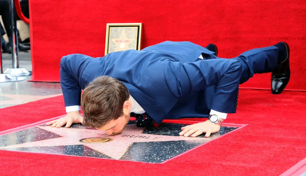 Michael Buble mencium bintang Hollywood Walk Of Fame miliknya saat acara penghargaan di Hollywood, California (16/11). Penyanyi Jazz asal Kanada ini merupakan penerima bintang ke 2,650 di Hollywood Walk Of Fame. (AFP Photo/David Livingston)