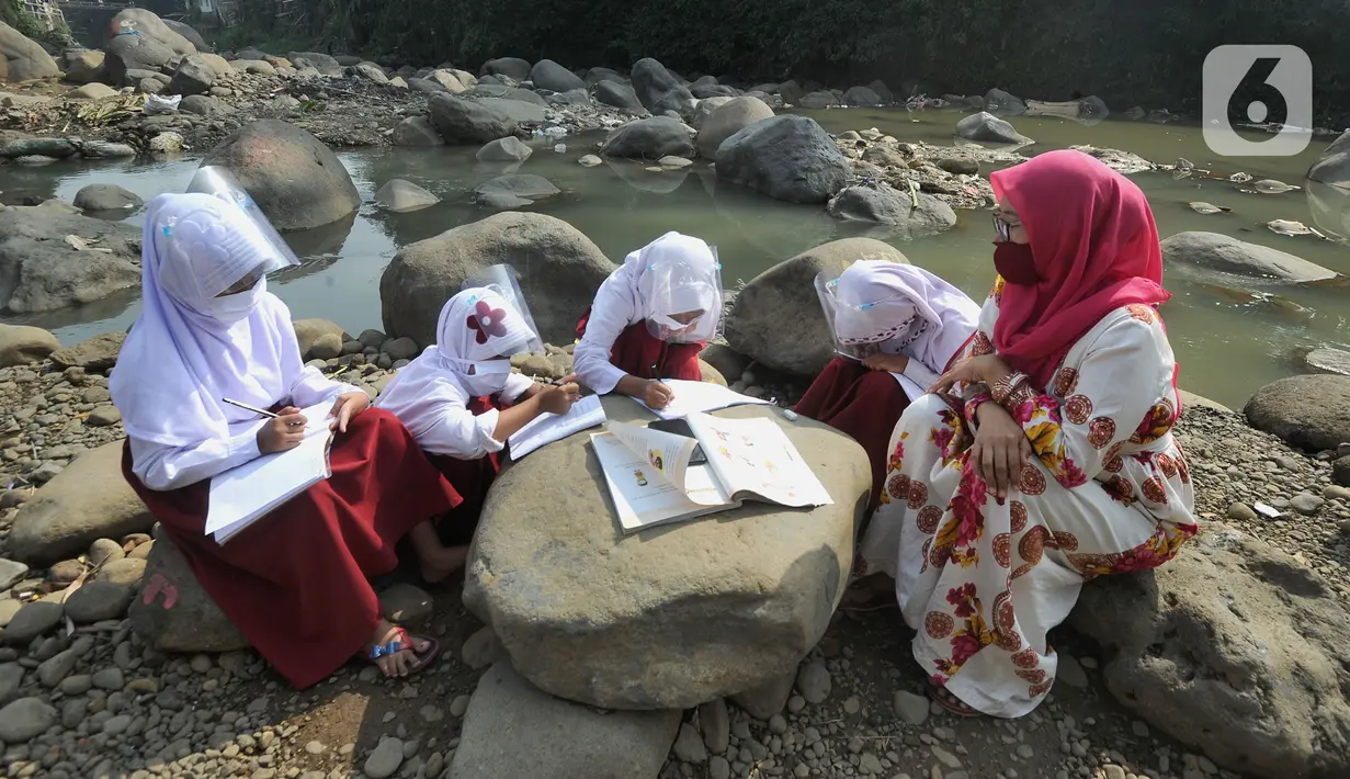 Siswa kelas 3 SDN II Roda Kota Bogor dan pendamping yang memiliki smartphone belajar kelompok secara daring di pinggir sungai Ciliwung, Kampung Kebon Jukut RT 01/10, Babakan Pasar, Kamis (6/8/2020). Kegiatan itu untuk mendapatkan jaringan internet yang baik di masa pandemi. (merdeka.com/Arie Basuki)