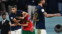 Pemain Prancis, Kylian Mbappe (kiri) menghibur pemain Maroko, Achraf Hakimi setelah laga semifinal Piala Dunia 2022 yang berlangsung di Al Bayt Stadium, Qatar, Rabu (14/12/2022) waktu setempat. Prancis menang dengan skor 2-0 melalui gol Theo Hernandez dan Randal Kolo Muani. (AFP/Gabriel Bouys)