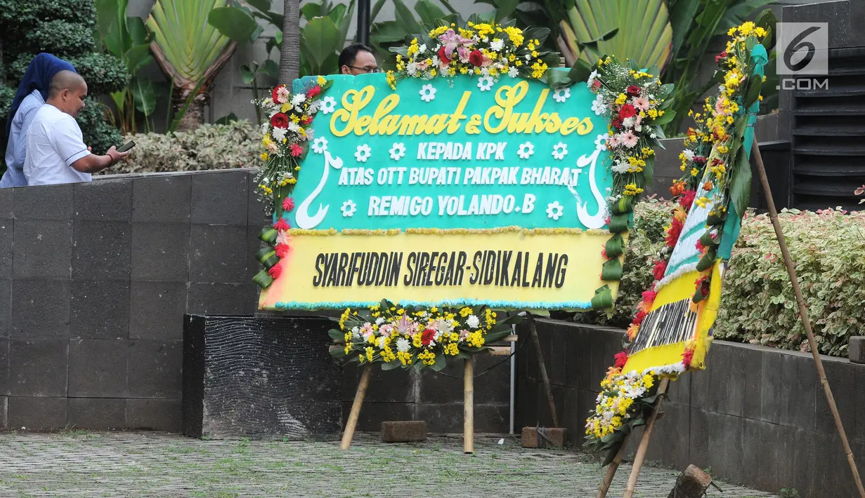 Sebuah karangan bunga menghiasi depan gedung KPK di Jakarta, Jumat (23/11). Karangan bunga tersebut sebagai ungkapan terima kasih atas operasi tangkap tangan (OTT) KPK terhadap Bupati Pakpak Bharat, Remigo Yolanda Berutu. (Merdeka.com/Dwi Narwoko)