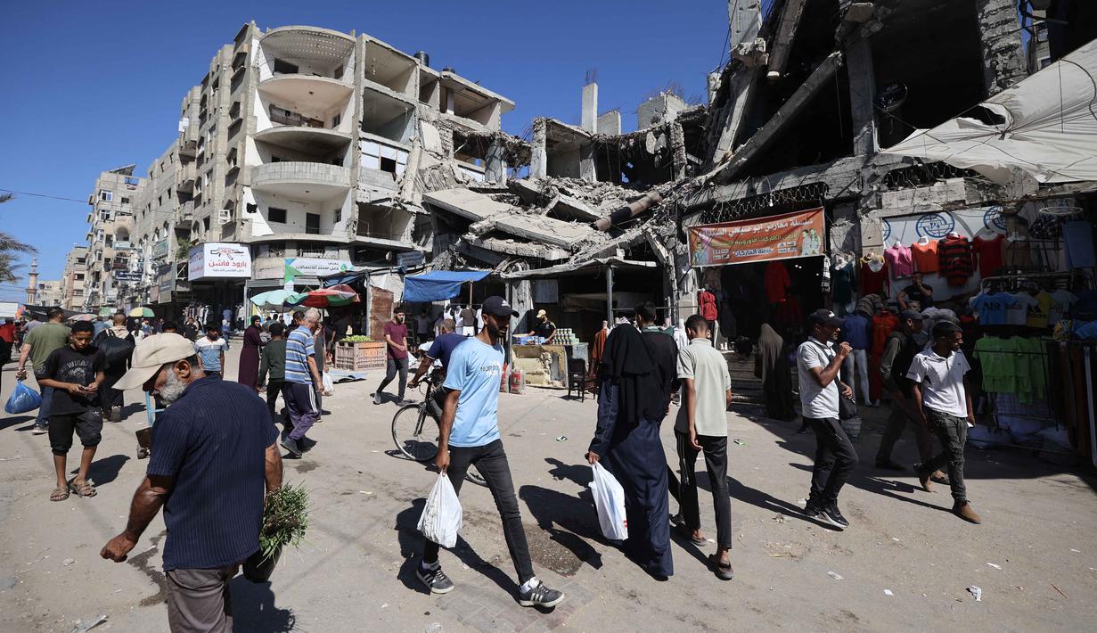 Di kamp pengungsi Nuseirat, pada 15 Oktober 2025, warga Palestina terpaksa berbelanja di pasar darurat yang dibangun di antara bangunan-bangunan yang hancur akibat serangan militer Israel. (Eyad BABA/AFP)