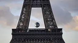 Sebuah bola besar tergantung disela Menara Eiffel, Perancis, (26/11). Karya seni ' Earth Crisis ' oleh seniman Amerika Shepard Fairey ditampilkan karena Paris menjadi tuan rumah Konferensi Perubahan Iklim Dunia 2015 (COP21). (REUTERS/Charles Platiau)