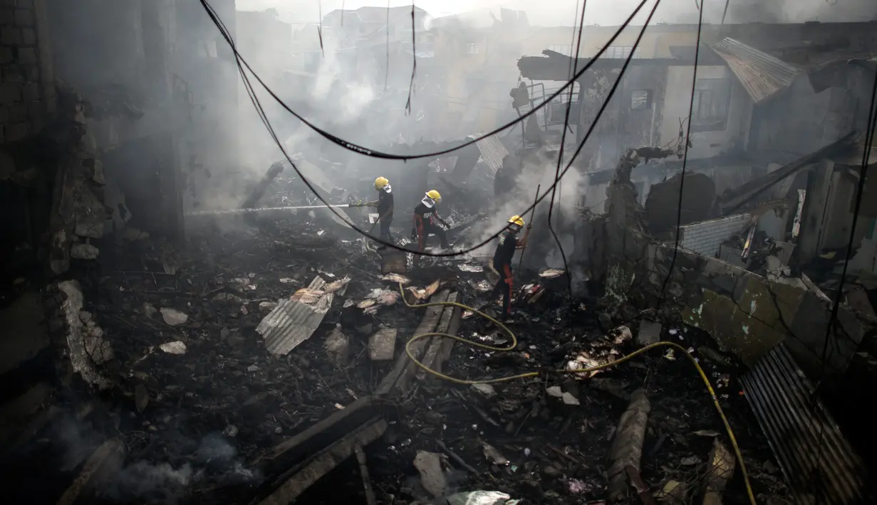 Petugas damkar memadamkan bara api yang masih tersisa di puing salah toko kembang api di wilayah Bocaue, 30 km dari Ibu Kota Filipina, Manila, Rabu (12/10). Sebuah kebakaran memicu ledakan dari kembang api yang ada di beberapa toko. (Noel Celis/AFP)