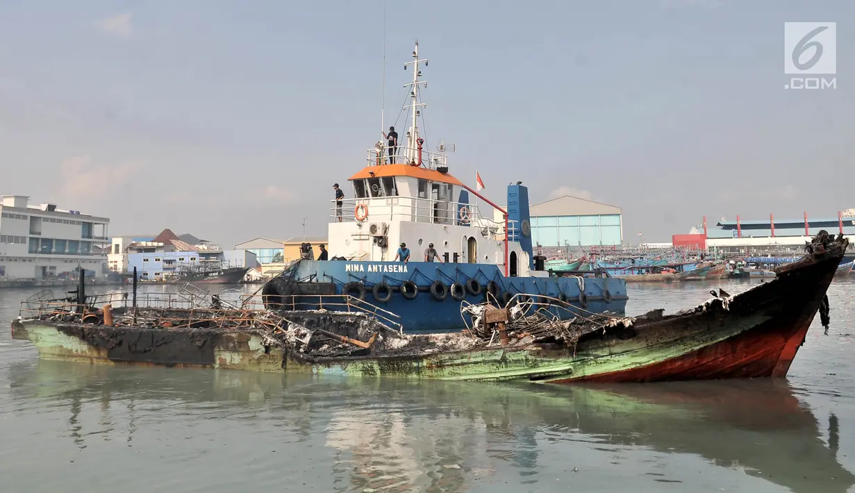 Petugas menggunakan kapal tongkang saat mengevakuasi sebuah kapal yang disebut titik awal kebakaran di Pelabuhan Muara Baru, Jakarta, Minggu (24/2). (Merdeka.com/Iqbal Nugroho)