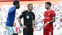 Gelandang Liverpool, Dominik Szoboszlai (merah) berkomunikasi dengan wasit dan pemain Everton dalam laga Derby Merseyside, Sabtu (21/10/2023) malam WIB. (AFP/Paul Ellis)