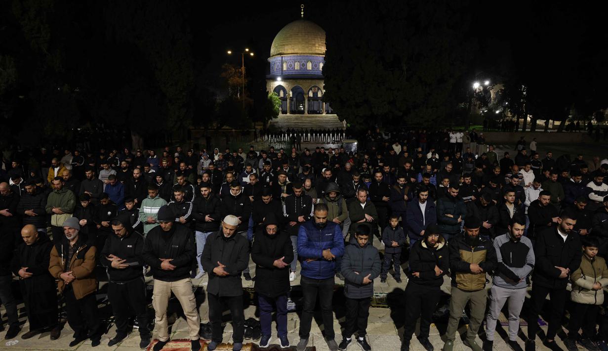 Para jamaah Muslim Palestina melaksanakan salat Tarawih pada malam pertama bulan suci Ramadan di dekat Kubah Batu, kompleks Masjid Al-Aqsa, Kota Tua Yerusalem pada 17 Februari 2026. (AHMAD GHARABLI/AFP)