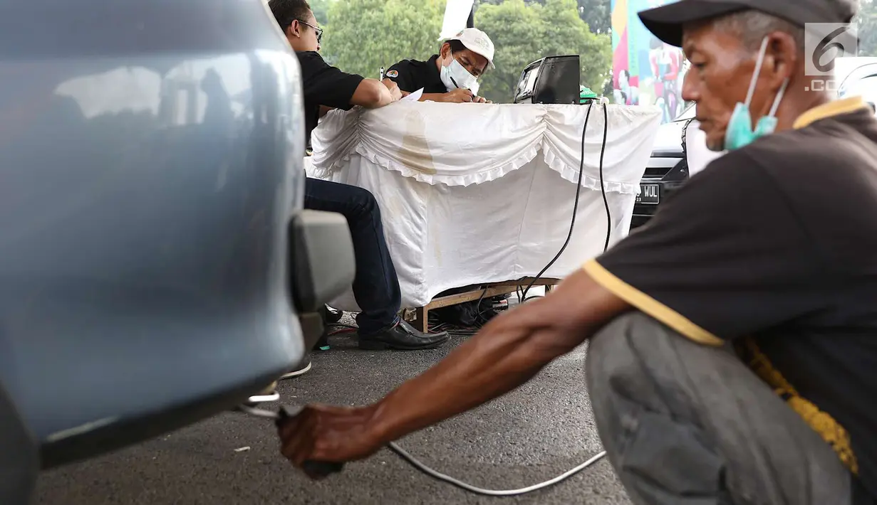 Petugas sudin lingkungan hidup mengisi form uji emisi gas buang kendaraan di kawasan Senayan, Jakarta, Rabu (18/7). Dinas Lingkungan Hidup bersama intansi terkait juga akan menerapkan sistem elektronik uji emisi. (Liputan6.com/Immanuel Antonius)