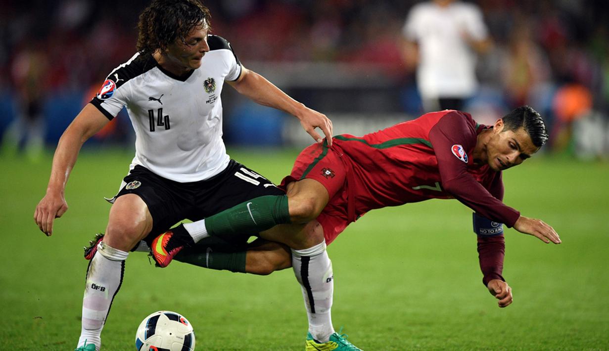 Striker Portugal, Cristiano Ronaldo, terjatuh saat berebut bola dengan pemain Austria, Julian Baumgartlinger, pada laga kedua Grup F Piala Eropa 2016 di Parc des Princes, Minggu (19/6/2016) dini hari WIB. (AFP/Martin Bureau)