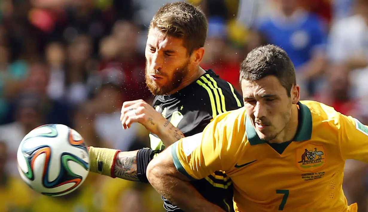 Pemain belakang Timnas Spanyol, Sergio Ramos (kiri) berebut bola dengan penyerang Australia, Matthew Leckie, di laga penyisihan Piala Dunia 2014 Grup B di Stadion Baixada, Curitiba, Brasil, (23/6/2014). (REUTERS/Stefano Rellandini)