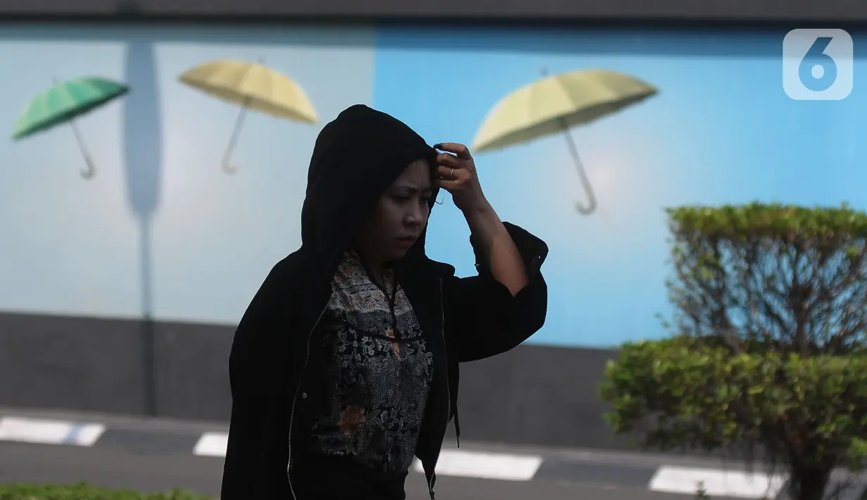 Pejalan kaki menutupi kepalanya dengan hoodie jaket untuk menghindari panas matahari di kawasan Kuningan, Jakarta, Selasa (26/9/2023). (merdeka.com/Imam Buhori)