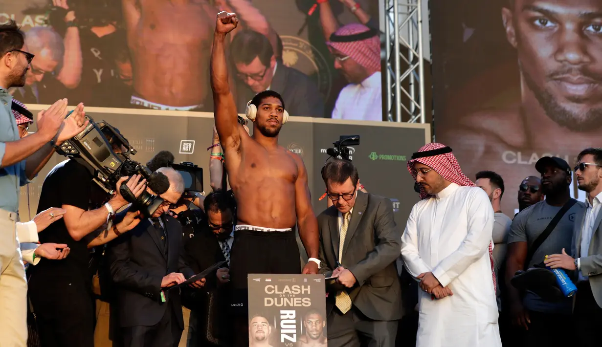 Petinju kelas berat Anthony Joshua (tengah) mengangkat tangannya saat timbang badan resmi di Riyadh, Arab Saudi, Jumat (6/12/2019). Anthony Joshua menantang Andy Ruiz Jr untuk merebut kembali sabuk juara kelas berat WBA, WBO, dan IBF. (AP Photo/Hassan Ammar)