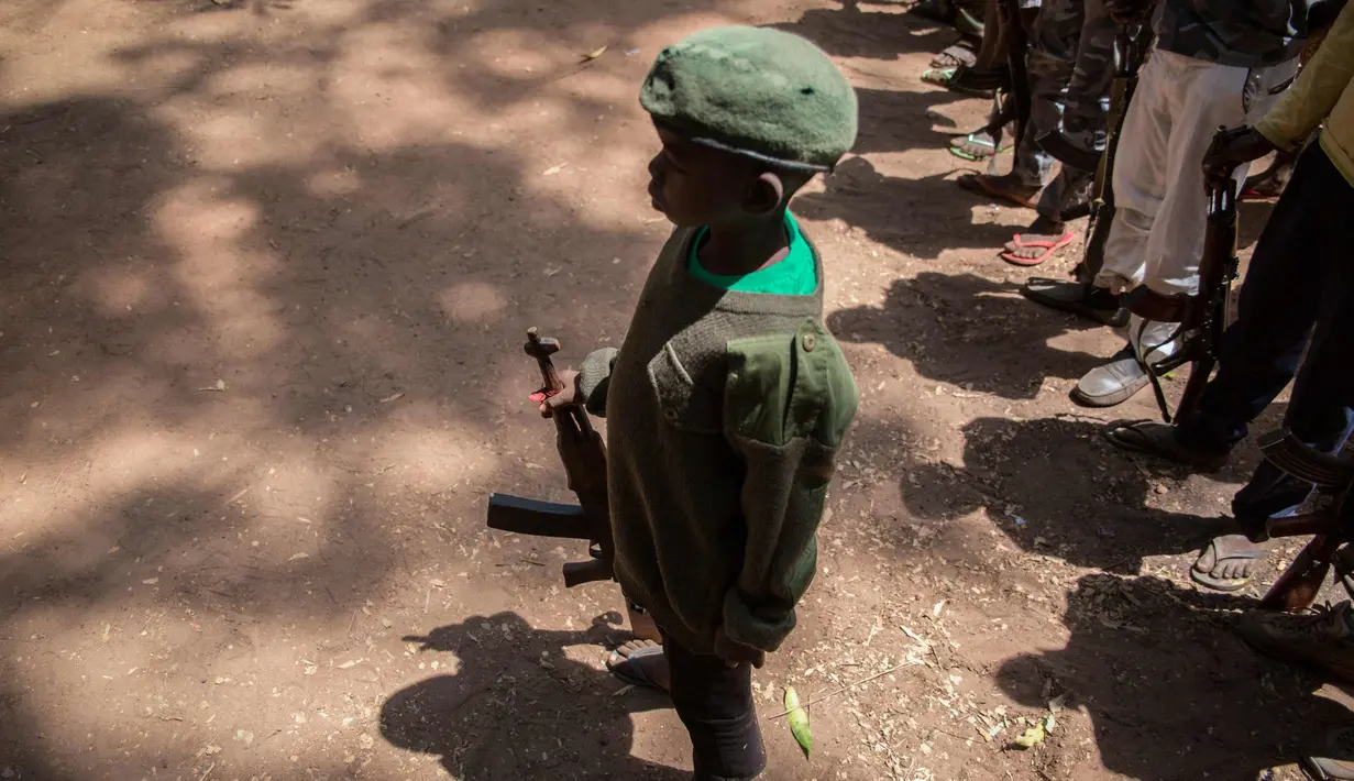 Tentara anak yang baru dibebaskan berdiri dengan senapan pada sebuah upacara di Yambio, Sudan Selatan, (7/2). Anak-anak ini secara resmi telah dilucuti senjatanya dan diberikan pakaian sipil. (AFP PHOTO/Stefanie Glinski)