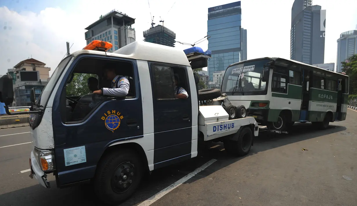 Petugas Dishub DKI Jakarta menderek bus Kopaja yang ngetem di kawasan Stasiun Sudirman, Jakarta (17/7). Dishub DKI melakukan razia rutin terhadap angkutan umum yang ngetem dan menyebabkan kemacetan  lalu lintas. (Merdeka.com/Arie Basuki)
