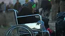 Seorang nenek dari Aleppo timur makan sambil duduk di kursi roda saat tiba di kota al-Rasyidin, Suriah (15/12). Konflik antara pemerintah dan pemberontak membuat kota Aleppo hancur. (REUTERS/Ammar Abdullah)