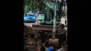 Seorang pekerja dibantu alat berat mengeruk saluran air di Jalan Latuharhari, Jakarta, Jumat (14/11/2014). (Liputan6.com/Faizal Fanani)