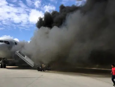 Penumpang dievakuasi dari pesawat Boeing 767-200ER milik maskapai Dynamic International Airways yang terbakar saat akan lepas landas di Bandara Fort Lauderdale, Florida, Kamis (29/10). 15 orang terluka akibat kejadian tersebut. (AFP PHOTO/Andres Gallego)