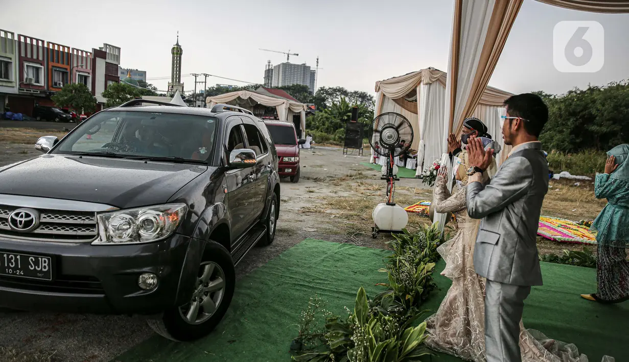 Pasangan mempelai bersama keluarga saat menyapa tamu undangan pada acara resepsi pernikahan secara "drive thru" di Bekasi, Jawa Barat, Sabtu (8/8/2020). Resepsi pernikahan secara drive thru menjadi alternatif pesta pernikahan guna mencegah penyebaran wabah COVID-19. (Liputan6.com/Faizal Fanani)