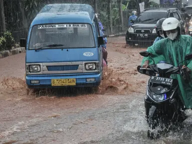 Pengendara mendorong sepeda motor saat melintasi genangan lumpur di Jalan Raya Sawangan, Depok, Minggu (7/11/2021). Hujan deras yang mengguyur Depok dan sekitarnya menyebabkan Jalan Raya Sawangan  digenangi banjir lumpur dan membahyakan keselamatan pengendara. (merdeka.com/Iqbal S Nugroho)