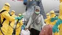 Petugas menyemprotkan cairan disinfektan ke WNI yang dievakuasi dari Wuhan, China saat tiba di bandara internasional Hang Nadim, Batam, Minggu (2/2/2020). Para WNI langsung ke luar pesawat untuk selanjutnya menuju Natuna, Kepulauan Riau. (Photo by Handout/Indonesian Embassy/AFP)