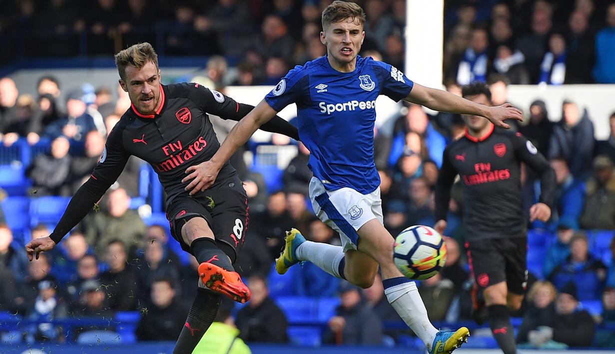 Pemain Arsenal, Aaron Ramsey (kiri) melepaskan tembakan saat diadang pemain Everton pada laga Premier League pekan ke-9 di Goodison Park, Liverpool, (22/10/2017). Arsenal menang 5-2. (AFP/Oli Scarff)