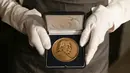 Seorang karyawan galeri memegang Medali Albert Einstein yang dianugerahkan kepada fisikawan Stephen Hawking selama sesi pemotretan untuk acara pelelangan di Balai Lelang Christie, London, Selasa (30/10). (Daniel LEAL-OLIVAS/AFP)
