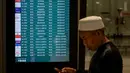 Perubahan jadwal penerbangan imbas ketegangan antara Amerika Serikat-Israel dengan Iran yang berdampak pada lalu lintas udara internasional. Tampak dalam foto, seorang pria menggunakan ponsel pintarnya sambil berjalan melewati papan informasi penerbangan saat Warga Negara Indonesia yang kembali dari Iran tiba di Bandara Internasional Soekarno-Hatta, Tangerang, Banten, pada Selasa 10 Maret 2026. (BAY ISMOYO/AFP)