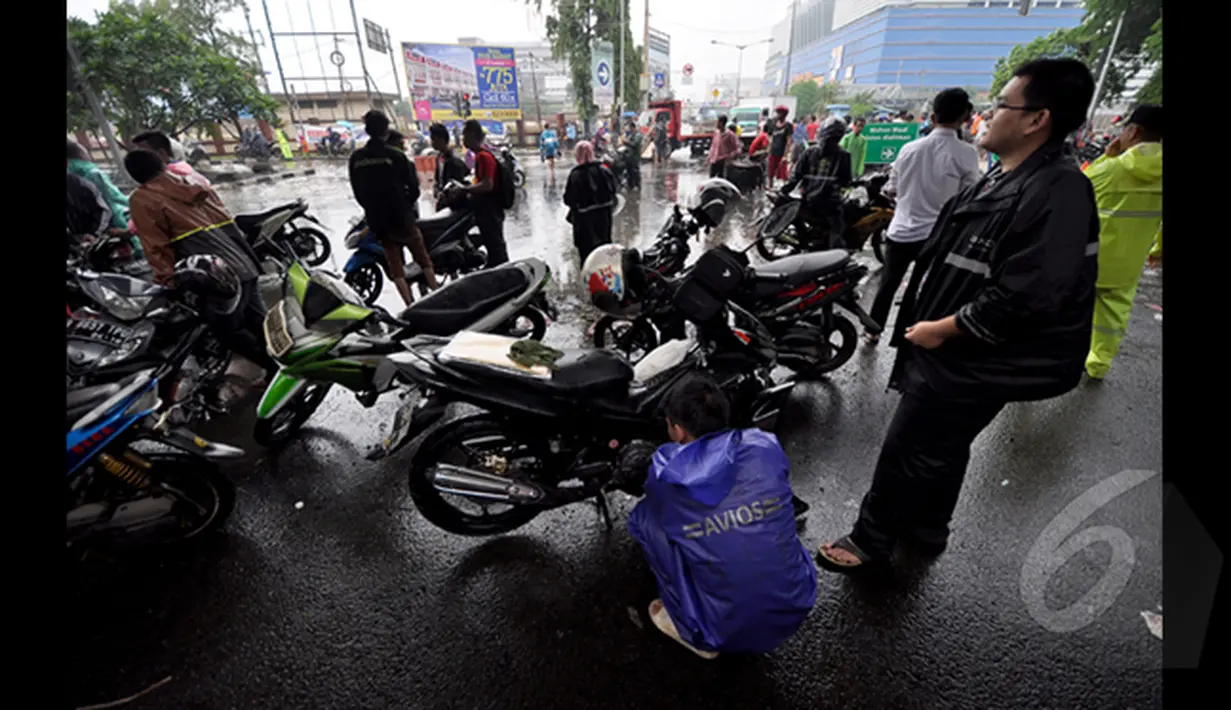 Seorang Pengendara saat melihat mesin motornya yang mati akibat melewati banjir, Jakarta, Senin (6/2/2015).  Hujan yang turun sejak malam hingga kini membuat sejumlah ruas jalan tergenang air. (Liputan6.com/Faizal Fanani)