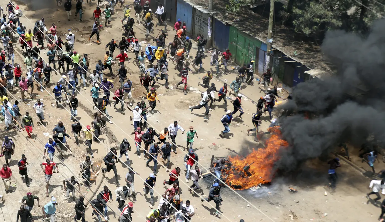 Para pengunjuk rasa berlari ke arah petugas polisi anti huru hara saat unjuk rasa massal di Kibera Slums, Nairobi, Senin, 27 Maret 2023. (AP Photo/Brian Inganga)