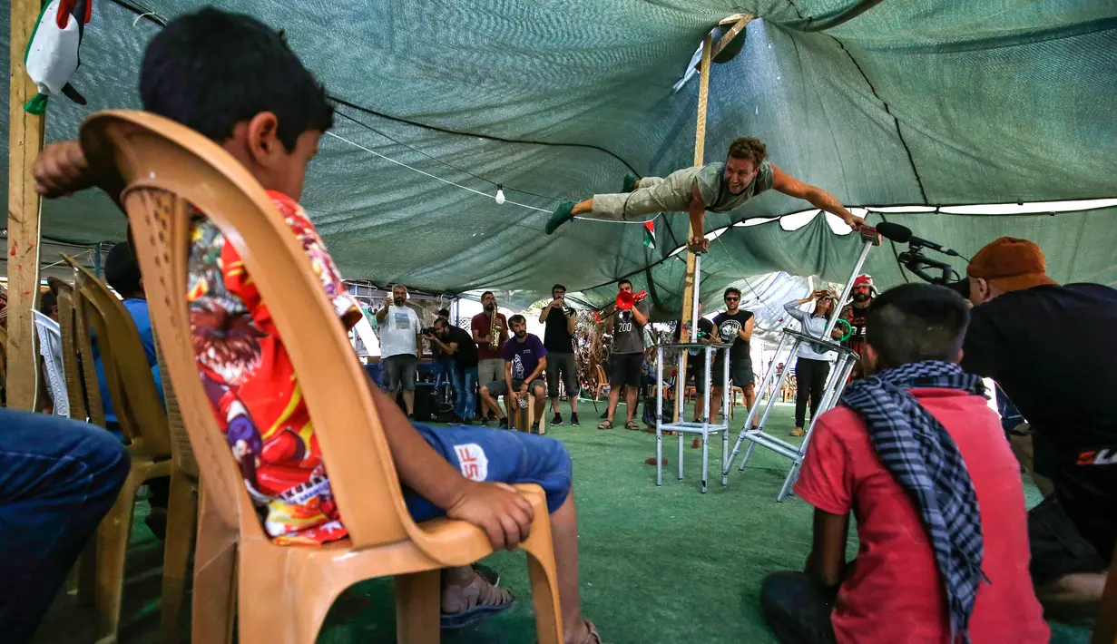 Rombongan badut Spanyol menghibur anak-anak Palestina di desa suku Bedouin, Tepi Barat yang diduduki, 22 September 2018. Atraksi ini dilakukan lantaran desa berpenduduk sekitar 180 orang itu akan digusur Israel pada Oktober mendatang. (AFP/ABBAS MOMANI)