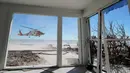Helikopter Penjaga Pantai AS terlihat lepas landas dari dalam rumah yang rusak akibat Badai Ian di Pulau Sanibel, Florida, 30 September 2022. Badai Ian tengah jadi sorotan di AS, sebab terjangannya begitu dahsyat hingga meninggalkan jejak kerusakan dan korban jiwa. (AP Photo/Steve Helber)
