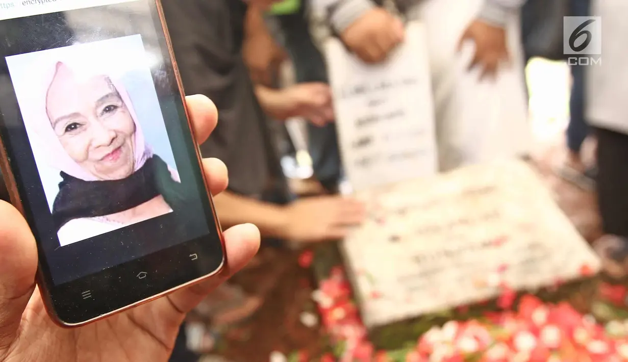 Keluarga menunjukkan foto Laila Sari saat dimakamkan di Tempat Pemakaman Umum (TPU) Karet Bivak, Jakarta, Selasa (21/11). Laila Sari meninggal dunia saat pulang syuting, di usai 82 tahun. (Liputan6.com/Herman Zakharia)