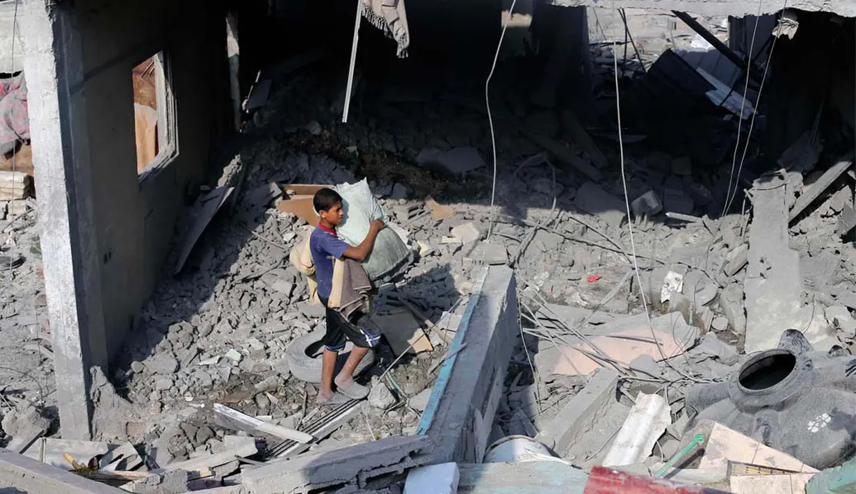 Seorang bocah tampak mencari sisa barang kepunyaan miliknya di antara reruntuhan bangunan akibat serangan udara Israel (REUTERS/Ibraheem Abu Mustafa)
