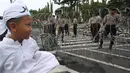 Seorang anak melintasi petugas polisi yang sedang memasang kawat berduri di sekitar Istana Negara, Jakarta, Jumat (31/3). Kawat berduri tersebut dipasang untuk mengantisipasi ricuh aksi 31 Maret. (Liputan6.com/Immanuel Antonius)
