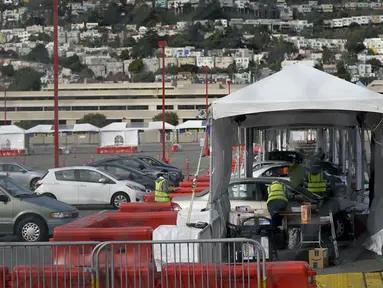 Mobil-mobil menunggu untuk mendapatkan vaksin COVID-19 di pusat vaksinasi drive-thru di City College of San Francisco di San Francisco, Senin (1/2/2021). Ketika pasokan vaksin COVID-19 meningkat, UC San Francisco memperluas upaya vaksinasi kepada mereka yang paling berisiko. (AP Photo/Jeff Chiu)